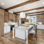 Brown-stained and white kitchen perimeter and island cabinets. Island includes decorative legs and seating.