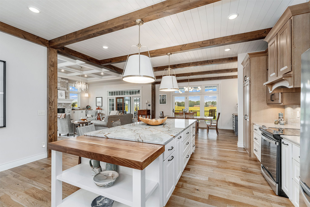 Brown-stained and white kitchen perimeter and island cabinets. Island includes decorative legs and seating.