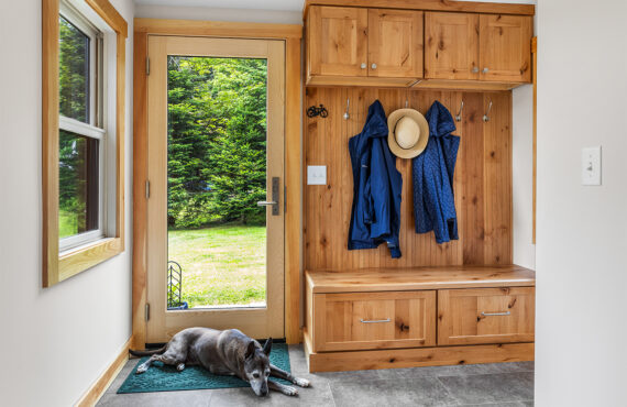 Rustic Alder mudroom locker and seating with drawers under the wood top. Dog is lying on a rug by the back door.