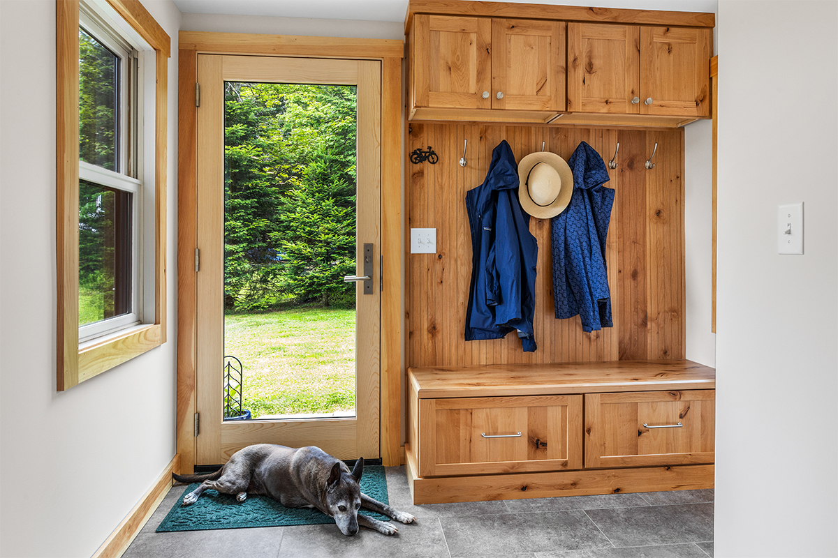 Rustic Alder mudroom locker and seating with drawers under the wood top. Dog is lying on a rug by the back door.