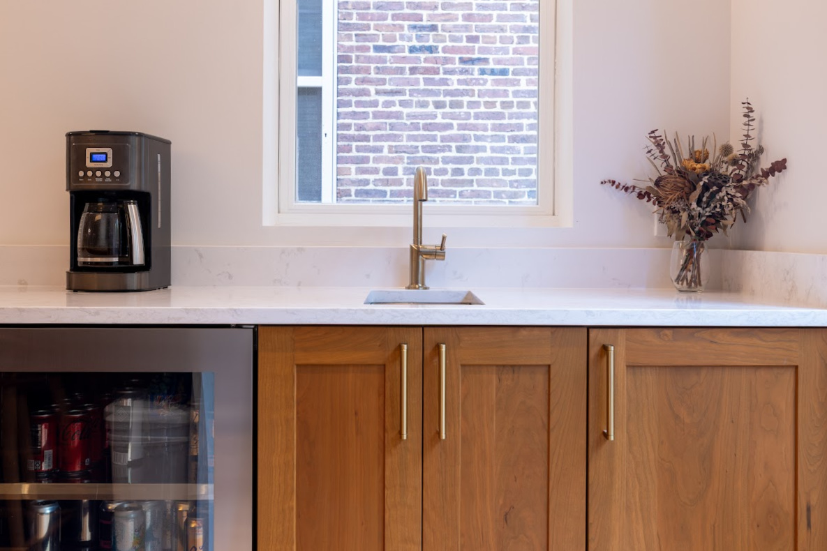 Cherry kitchen cabinets with a red Sienna stain. Small sink below a window is showing.