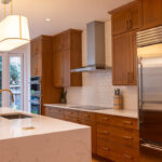 Cherry kitchen cabinets with a red Sienna stain. view shows stainless steel appliances on hood.