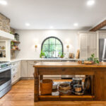 Old World style kitchen with Light Mocha-painted perimeter and a custom wood island in a mid-brown stain.