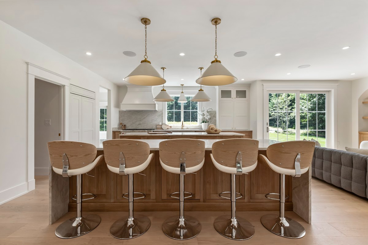 White and light brown kitchen cabinets. View is from the front of the island facing the hood and window.