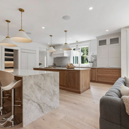 White and light brown kitchen cabinets. View is from the front of the island facing the hood and window.