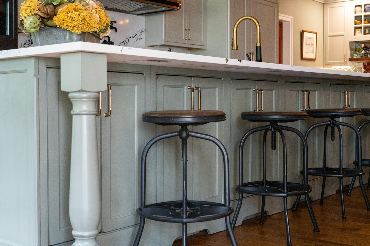 Painted Oyster primary kitchen cabinets with black appliances and green island.