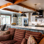 Painted Oyster primary kitchen cabinets with black appliances and green island.