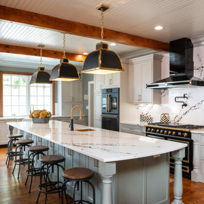 Painted Oyster primary kitchen cabinets with black appliances and green island.