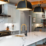 Painted Oyster primary kitchen cabinets with black appliances and green island.