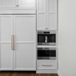 kitchen with white refrigerator panels attached with a double oven cabinet to the right.