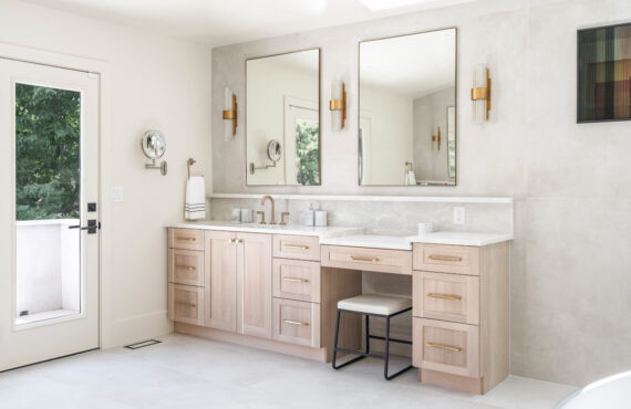 Light stained bathroom vanity with powder desk and two contemporary mirrors.