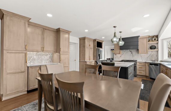 Kitchen cabinets with light brown stain. Shows a gray painted wood hood and stainless steel oven.