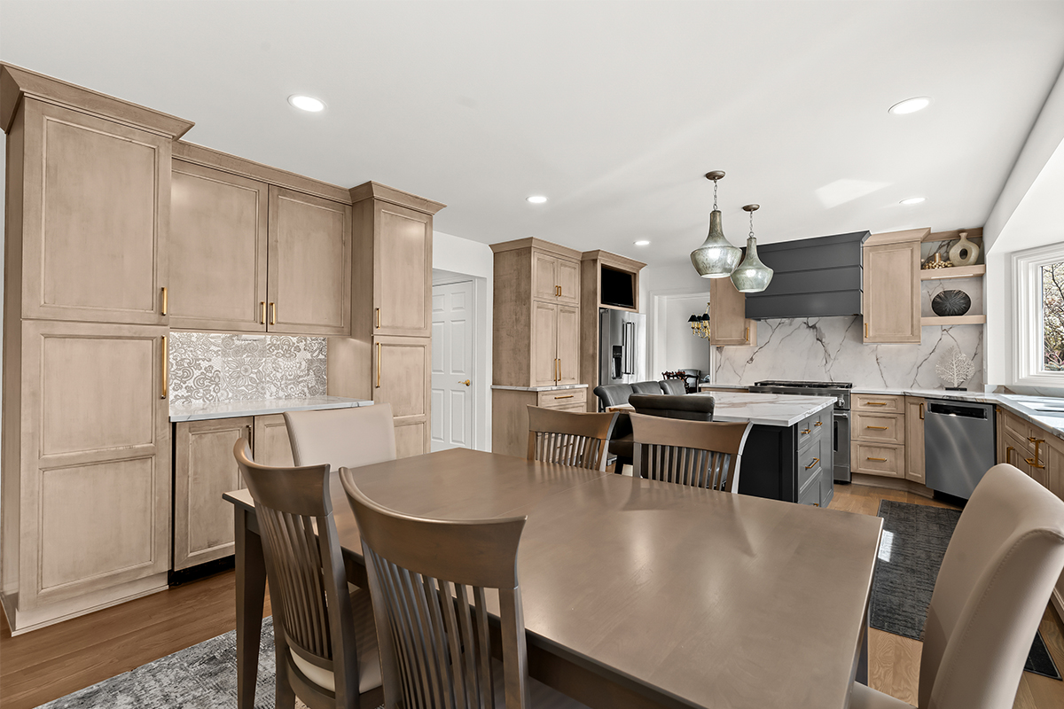 Kitchen cabinets with light brown stain. Shows a gray painted wood hood and stainless steel oven.