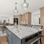 Kitchen cabinets with light brown stain. Shows a gray painted island.