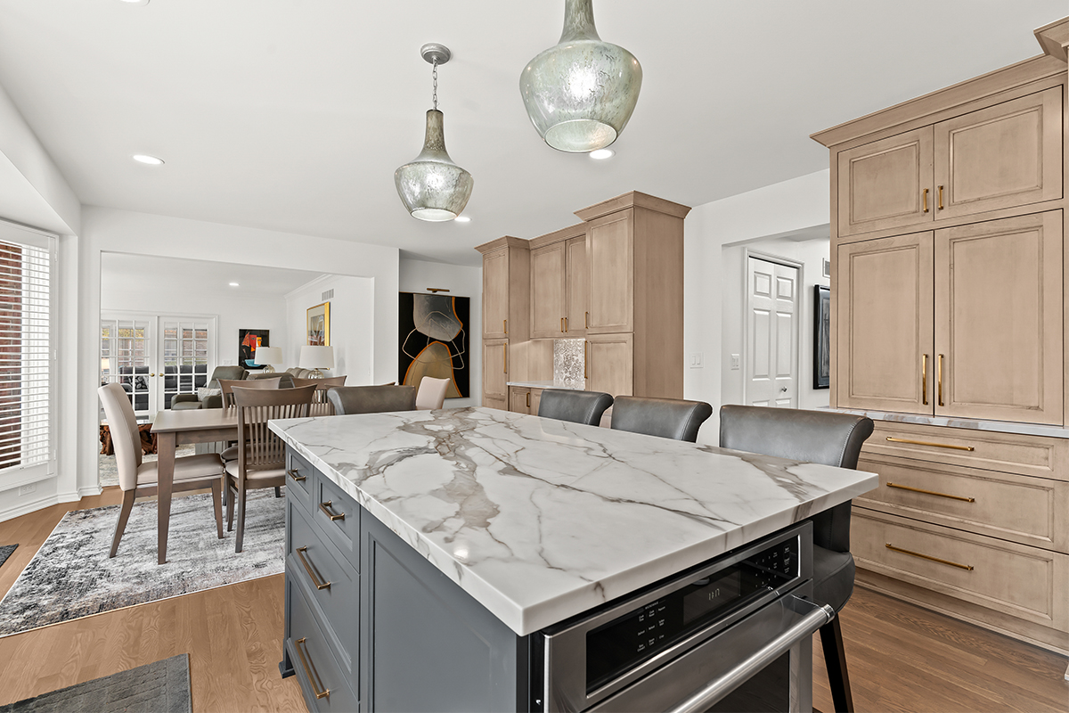 Kitchen cabinets with light brown stain. Shows a gray painted island.