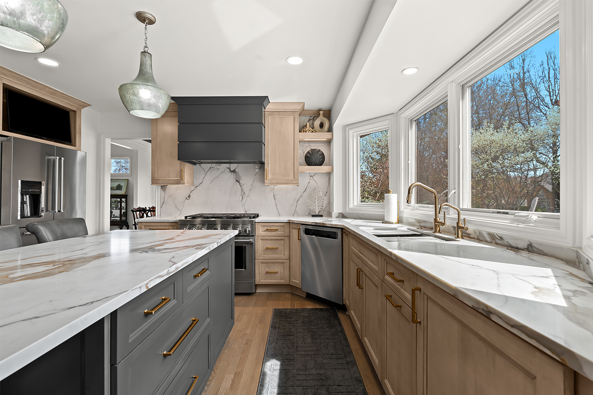 Kitchen cabinets with light brown stain. Shows a gray painted island.
