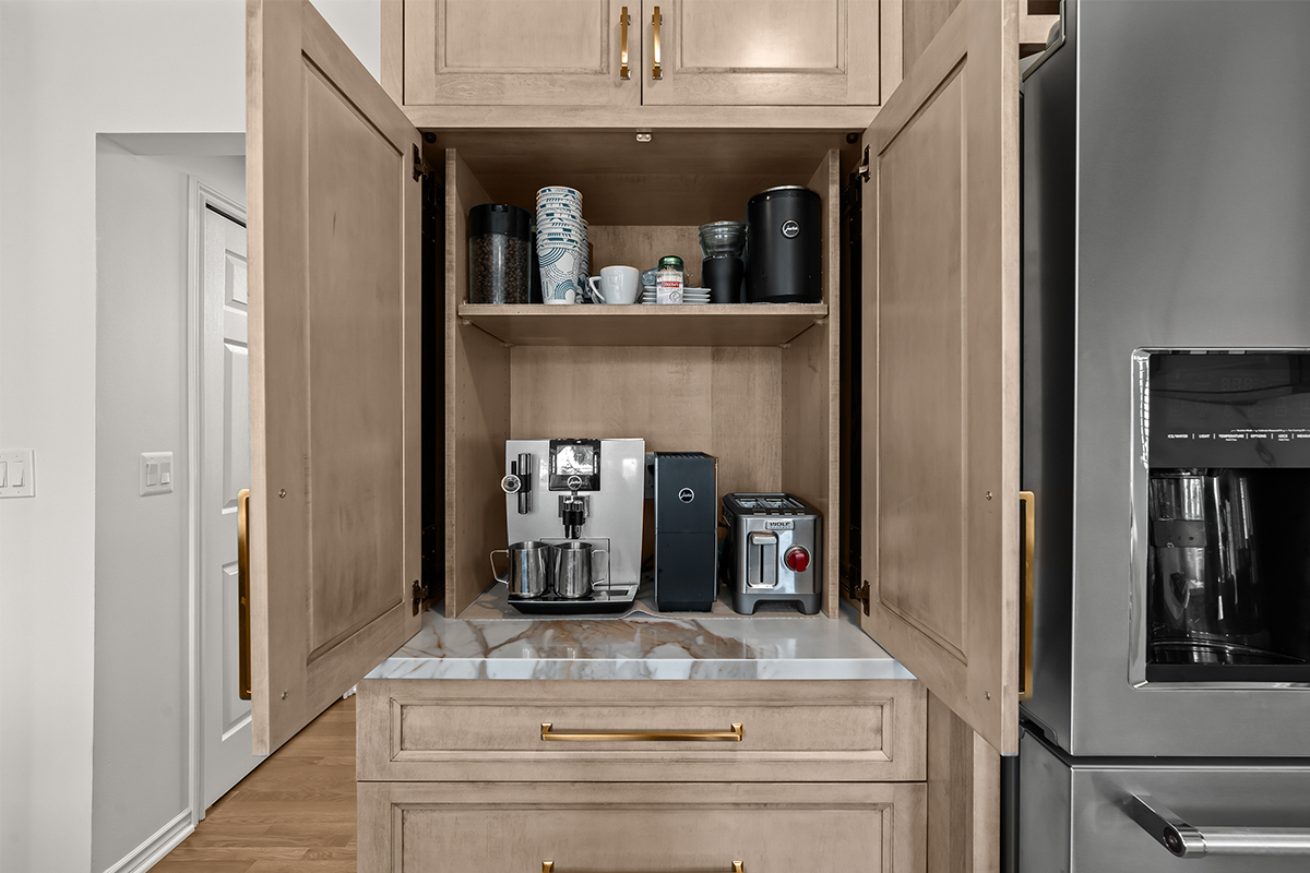 Kitchen cabinets with light brown stain. Shows pocket doors open in a coffee center cabinet.