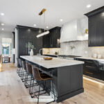 Kitchen with dark Iron Ore painted cabinets and a white hood. Includes a long island with seating.