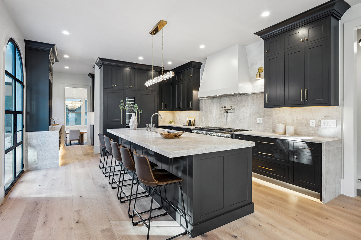 Kitchen with dark Iron Ore painted cabinets and a white hood. Includes a long island with seating.