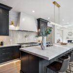 Kitchen with dark Iron Ore painted cabinets and a white hood. Includes a long island with seating.