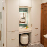 White painted linen cabinets with powder desk mounted between them.