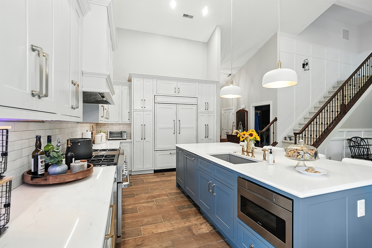 White kitchen perimeter cabinets with blue island.