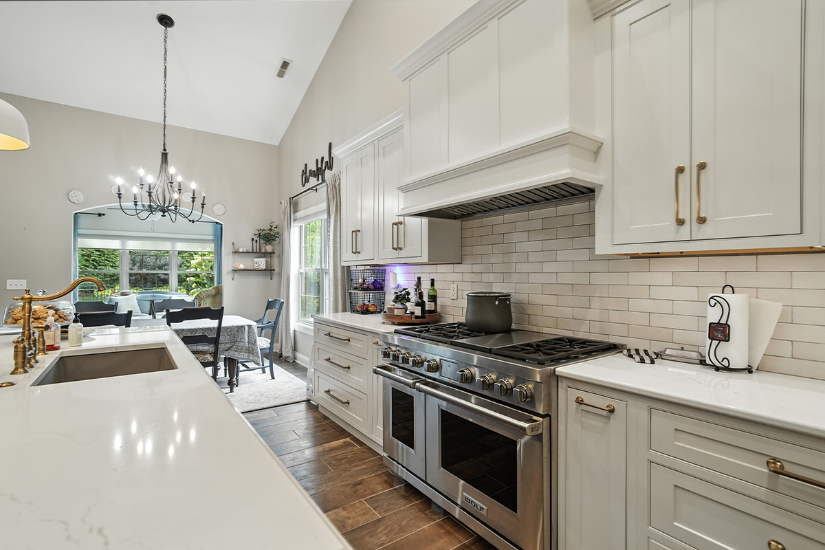 White kitchen cabinets with wood hood and stainless-steel professional oven.