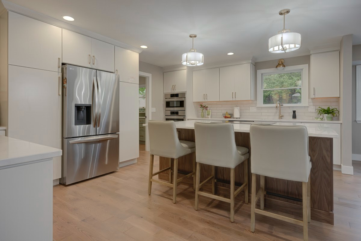 White painted kitchen cabinets with island seating and stainless steel fridge