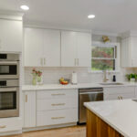 White painted kitchen cabinets with walnut natural island