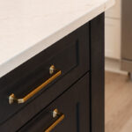 Light Mocha painted perimeter kitchen cabinets and an island with dark stained hood and island.