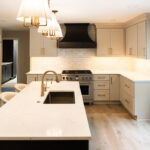 Light Mocha painted perimeter kitchen cabinets and an island with dark stained hood and island.
