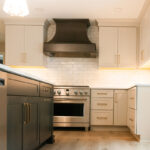Light Mocha painted perimeter kitchen cabinets and an island with dark stained hood and island.