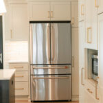 Light Mocha painted perimeter kitchen cabinets with stainless fridge.