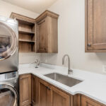 Brown stained laundry room with stacked washer and dryer