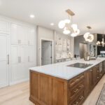 Beige painted kitchen perimeter cabinets with a 16-foot stained quartersawn white oak island wtih seating.