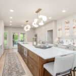 Beige painted kitchen perimeter cabinets with a 16-foot stained quartersawn white oak island wtih seating.