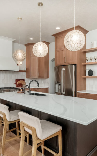 Light and dark stained kitchen with white counter and round hanging lights