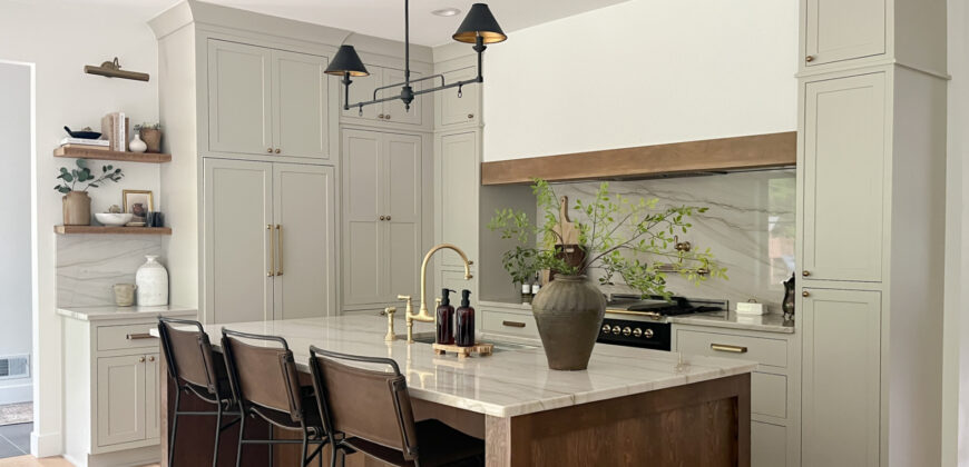 Light gray painted kitchen with white hood and stained wood island